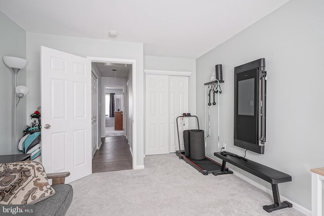 workout area featuring attic access, baseboards, and light colored carpet