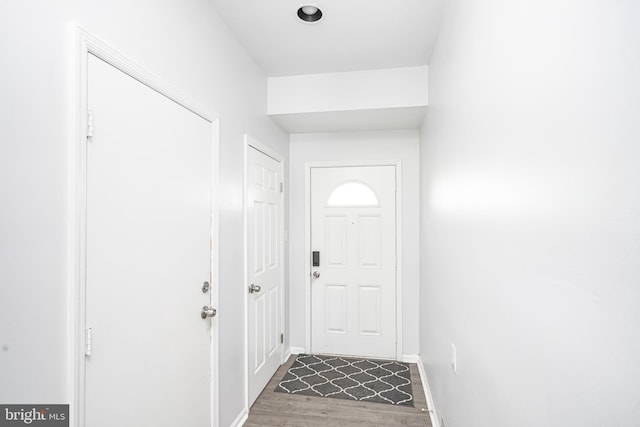 doorway with baseboards and dark wood-type flooring