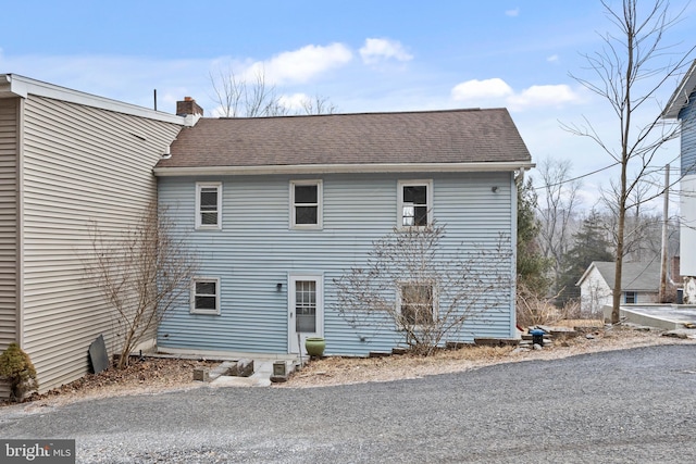 exterior space featuring roof with shingles and a chimney