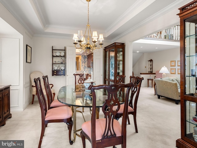 dining area featuring ornamental molding, an inviting chandelier, a raised ceiling, and light colored carpet