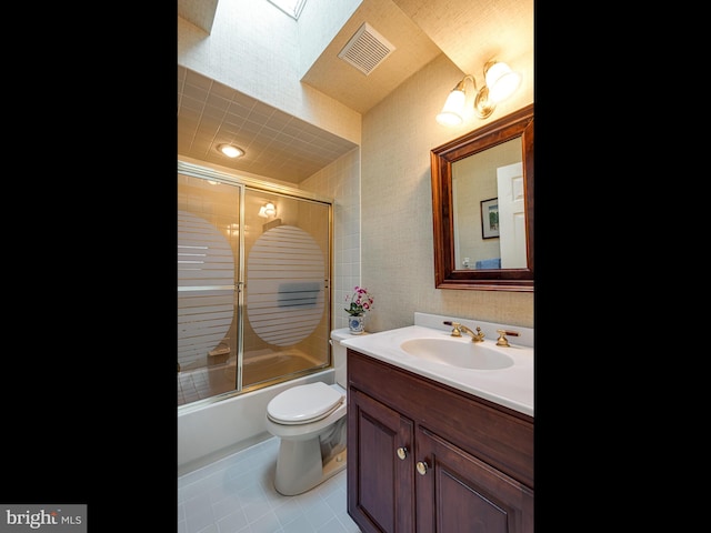 bathroom featuring bath / shower combo with glass door, visible vents, toilet, vanity, and tile patterned floors