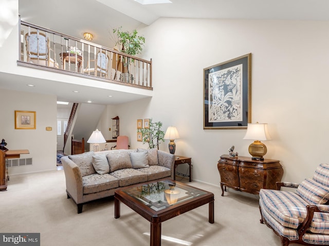 living room with light carpet, a skylight, stairway, and high vaulted ceiling