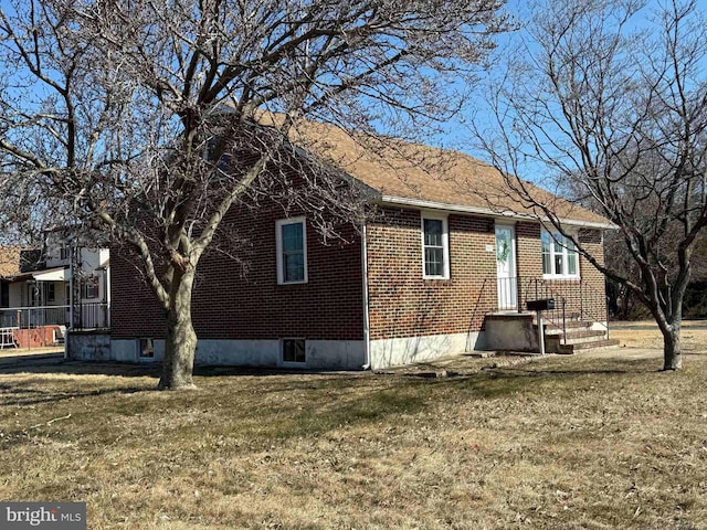 rear view of house featuring a yard and brick siding