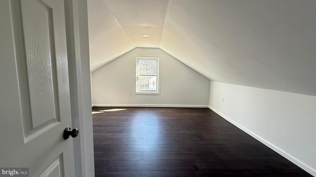 additional living space with lofted ceiling, baseboards, and dark wood-style flooring