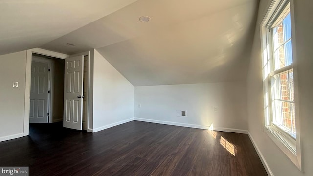 bonus room with dark wood-style flooring, visible vents, vaulted ceiling, and baseboards