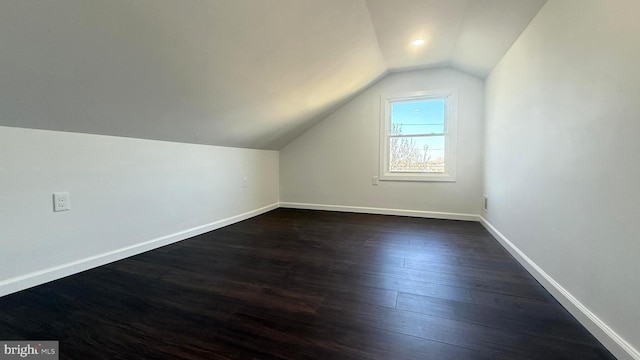 additional living space with dark wood-style floors, vaulted ceiling, and baseboards