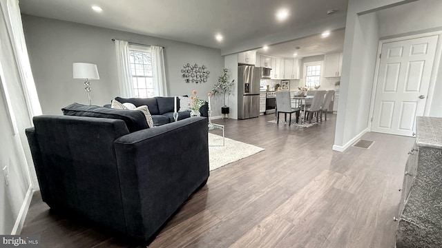 living area with baseboards, wood finished floors, and recessed lighting