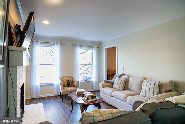 living room featuring ornamental molding, dark wood-style flooring, a brick fireplace, and baseboards