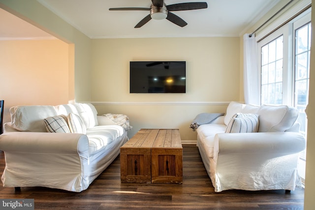 living room featuring dark wood-style flooring, crown molding, baseboards, and ceiling fan