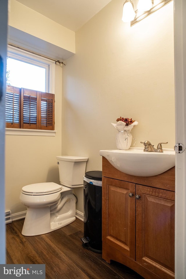 bathroom featuring toilet, baseboards, wood finished floors, and vanity