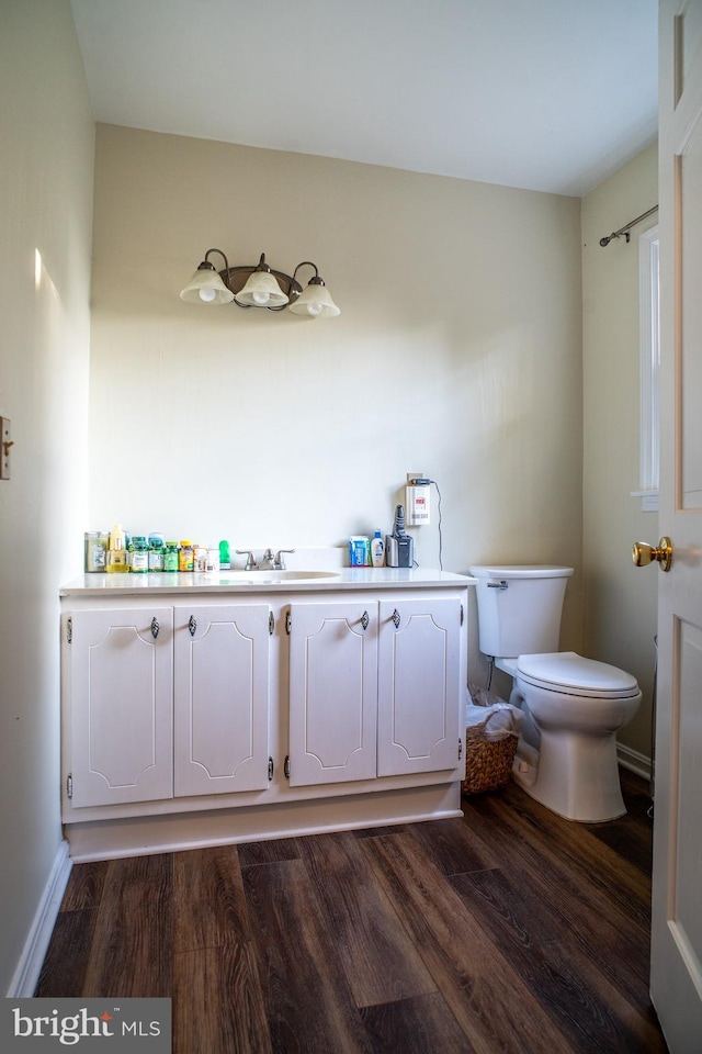 bathroom with baseboards, a sink, toilet, and wood finished floors