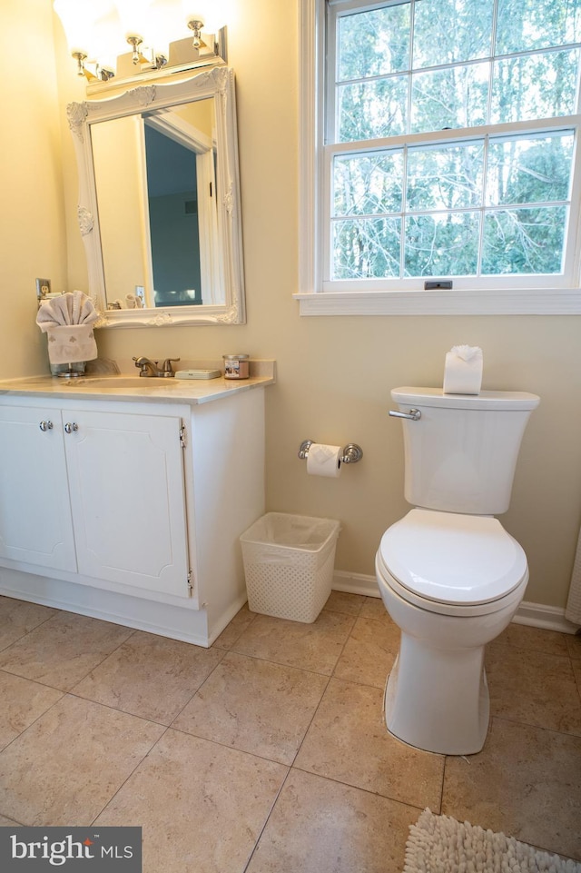 half bathroom featuring baseboards, vanity, toilet, and tile patterned floors