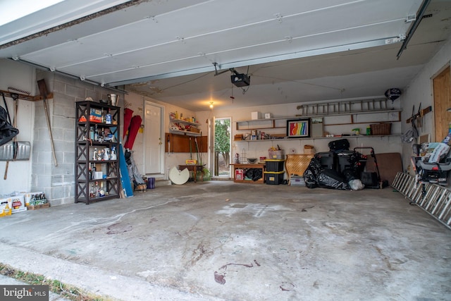 garage featuring concrete block wall and a garage door opener