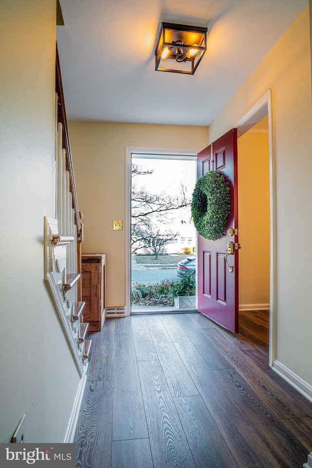 foyer entrance with stairway, baseboards, and wood finished floors