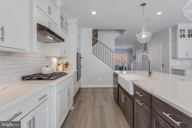 kitchen featuring dark brown cabinetry, under cabinet range hood, gas stovetop, white cabinetry, and a sink