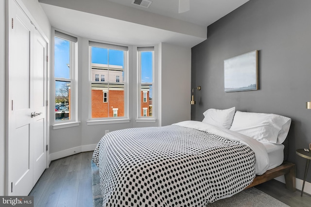 bedroom with visible vents, baseboards, and wood finished floors