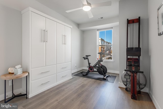 exercise room with ceiling fan, light wood-type flooring, visible vents, and baseboards