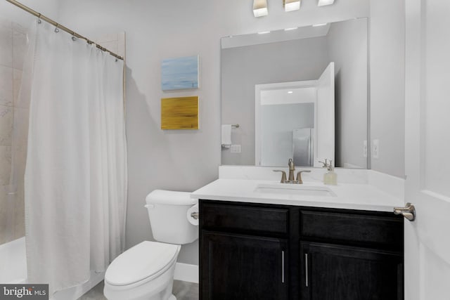 bathroom with a tile shower, vanity, and toilet