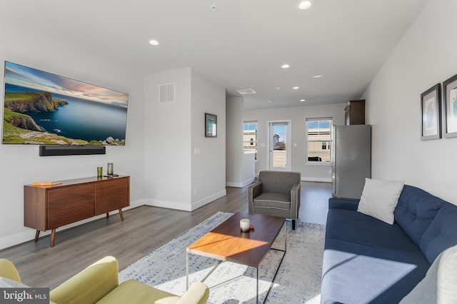 living room with baseboards, visible vents, wood finished floors, and recessed lighting