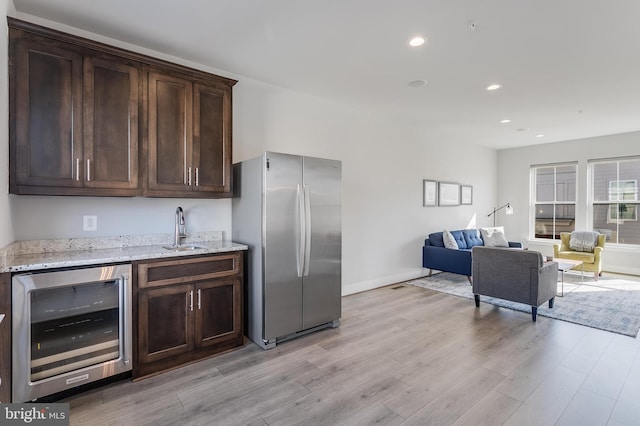 kitchen featuring beverage cooler, dark brown cabinets, a sink, and freestanding refrigerator