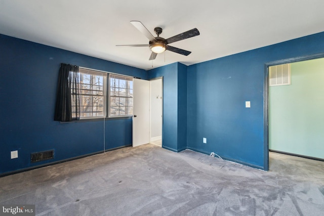 unfurnished room with carpet floors, visible vents, and a ceiling fan