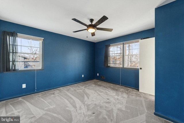 empty room featuring a wealth of natural light, ceiling fan, and carpet