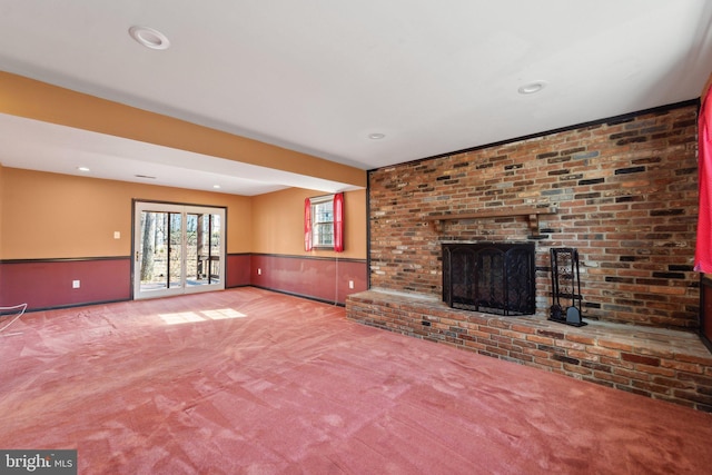 unfurnished living room with a wainscoted wall, recessed lighting, a fireplace, and carpet