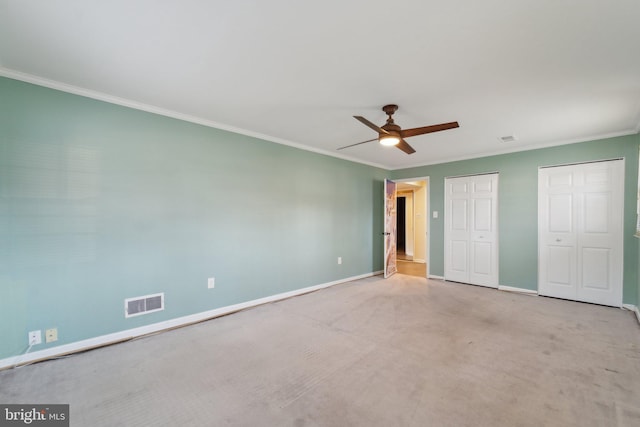 unfurnished bedroom with baseboards, two closets, visible vents, and crown molding