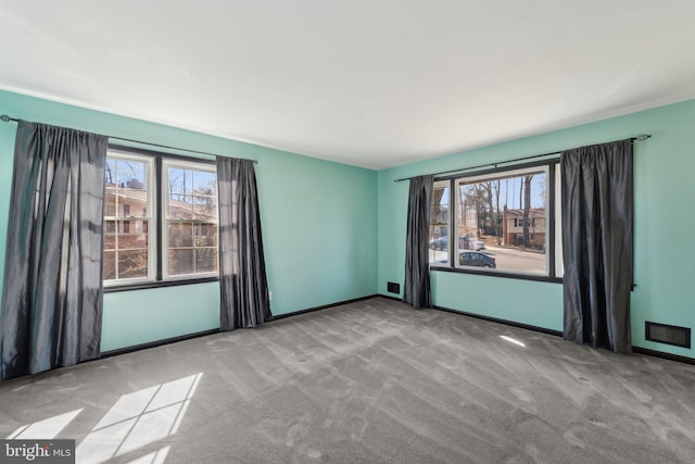 empty room with carpet floors, visible vents, and baseboards