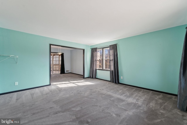 spare room featuring carpet floors and baseboards