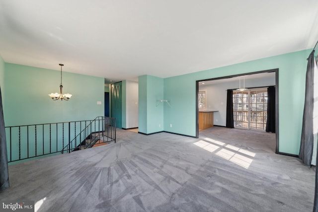 empty room with baseboards, a notable chandelier, and carpet flooring