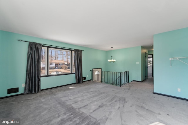 unfurnished room with baseboards, carpet flooring, visible vents, and a notable chandelier