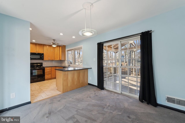 kitchen featuring visible vents, dark countertops, a sink, black appliances, and backsplash