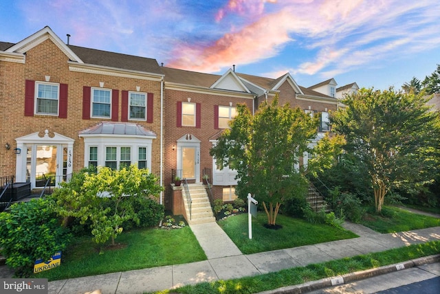 multi unit property featuring a front yard and brick siding