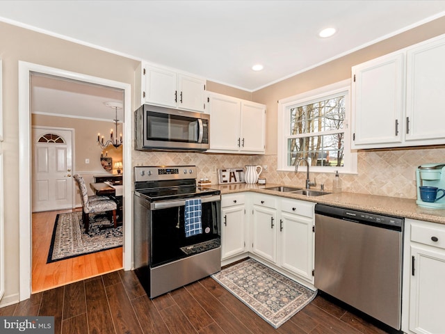 kitchen featuring stainless steel appliances, dark wood-type flooring, a sink, white cabinets, and crown molding