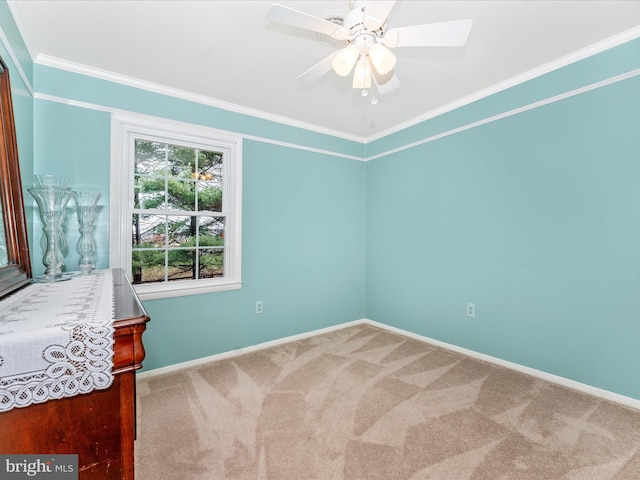 empty room featuring ornamental molding, carpet, a ceiling fan, and baseboards