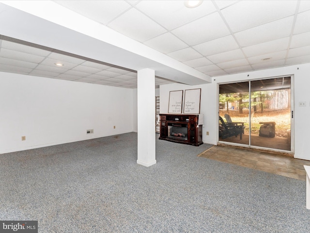 below grade area with carpet floors, a paneled ceiling, and a fireplace