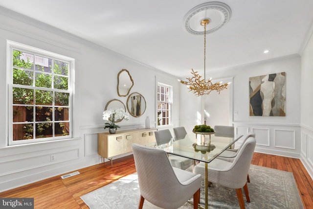 dining space with light wood-type flooring, visible vents, plenty of natural light, and a decorative wall