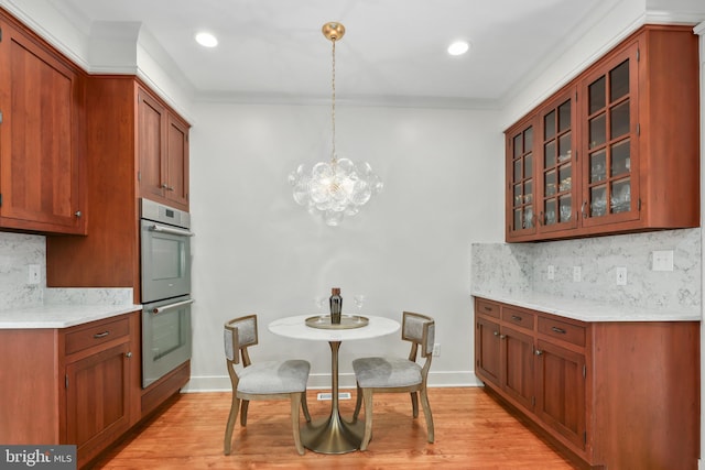 kitchen featuring glass insert cabinets, brown cabinets, hanging light fixtures, and double oven