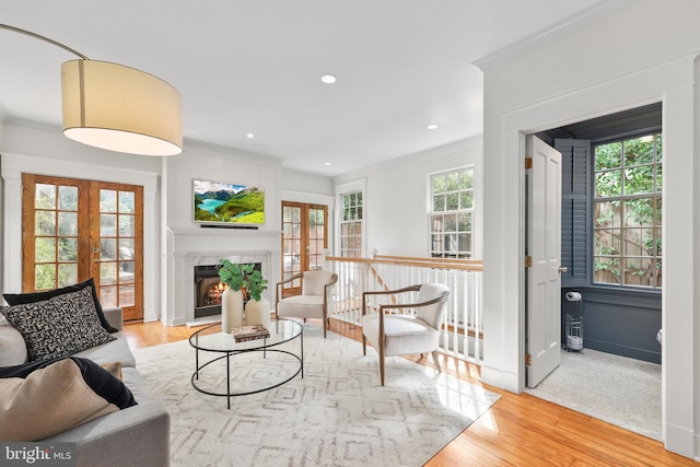 living room with light wood-style flooring, recessed lighting, baseboards, a lit fireplace, and french doors