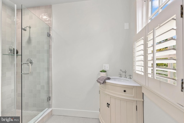 full bathroom with a stall shower, tile patterned flooring, vanity, and baseboards