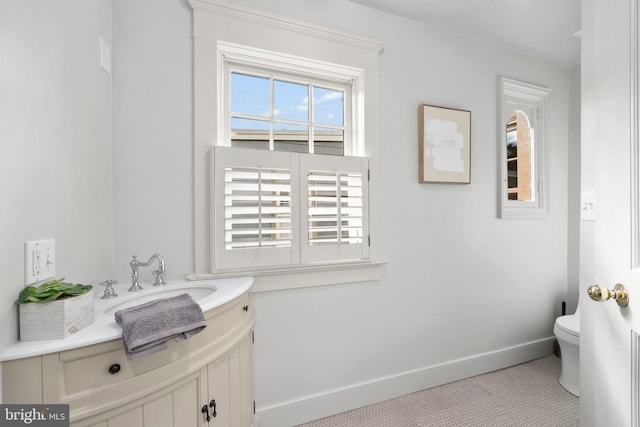 half bathroom with toilet, baseboards, and vanity