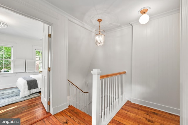 staircase featuring wood-type flooring, ornamental molding, and baseboards