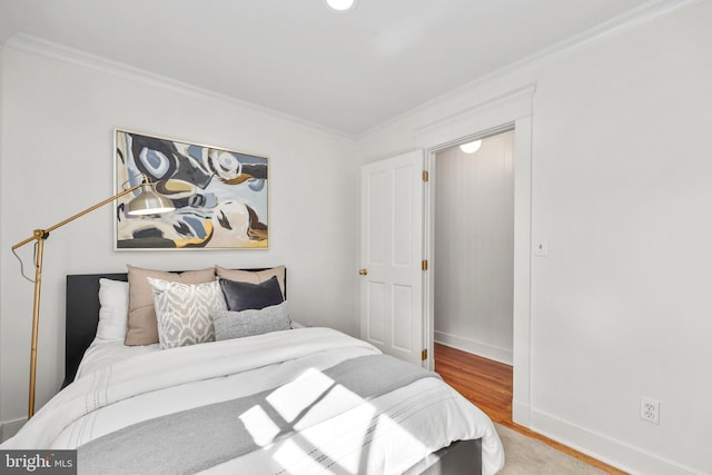 bedroom with crown molding, baseboards, and wood finished floors