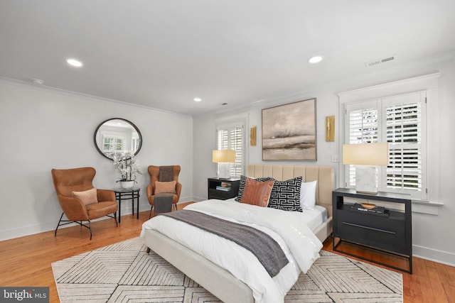 bedroom featuring crown molding, baseboards, visible vents, and light wood-style floors