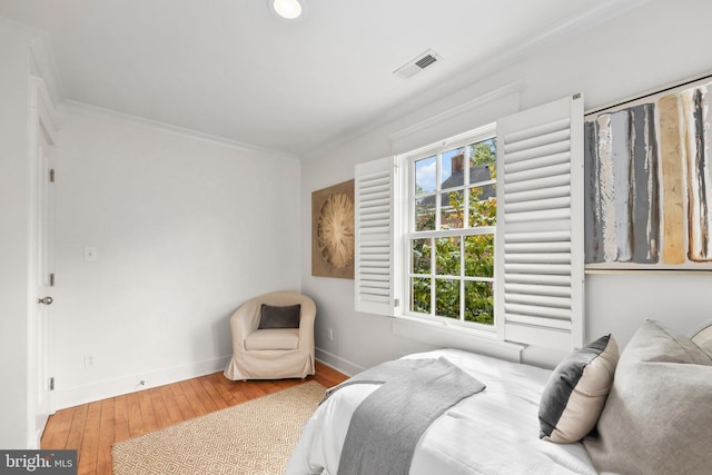 bedroom featuring visible vents, crown molding, baseboards, and wood finished floors