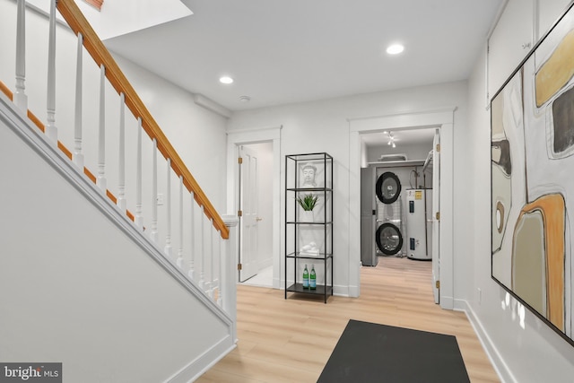 entryway with light wood-type flooring, water heater, baseboards, and stairs