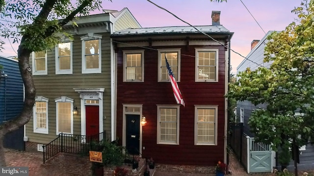 view of property with a standing seam roof, a chimney, and metal roof