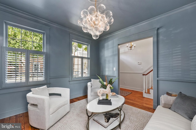 living area featuring stairway, wood finished floors, a notable chandelier, and ornamental molding