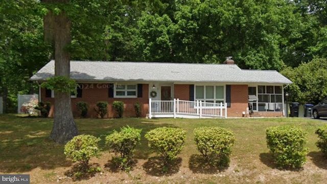 single story home featuring a front yard, covered porch, and brick siding